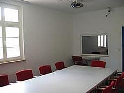 Ein Konferenzraum mit roten Stühlen und einem Spiegel