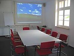 Ein Konferenzraum mit roten Stühlen und einem Whiteboard